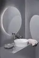 Elegante Waschbeckenarmatur von Ideal Standard mit hochglänzender Chromoberfläche. Einfache Bedienung, ideal für moderne Badezimmergestaltung. Runde Spüle auf grauem Unterschrank.
